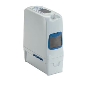 The Inogen Rove 6 System - North America 16 Cell is a portable oxygen concentrator featuring a digital display, top control buttons, and a side mesh-covered vent. It’s primarily white with blue accents.
